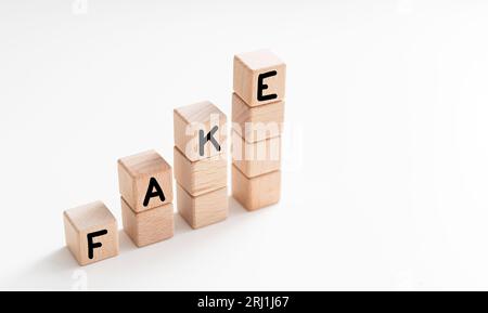 WORTFÄLSCHUNG aus HOLZWÜRFELN auf weißem Hintergrund. Stockfoto