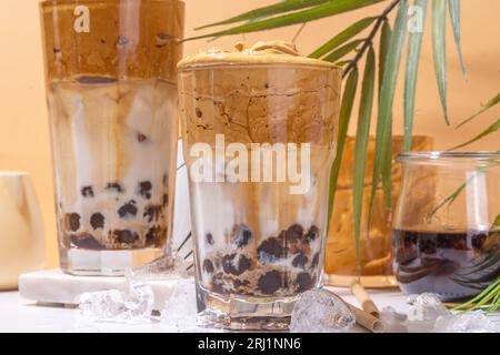Boba dalgona Kaffee. Trendiges asiatisches Latte-Morgengetränk mit Instant-Kaffee und Tapioka-Perlkugeln, thailändisches Schaumcocktail-Glas im Sommer in der Sonne Stockfoto