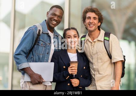 Glückliche Dame und zwei Jungs Schüler, die sich im Freien umarmen und lächeln Stockfoto