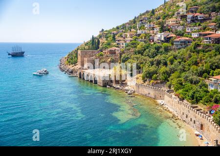 Alte Werft oder Tersane in der Nähe des Kizil Kule Turms und wunderschöner Strand und ruhige türkisfarbene Meeresoberfläche in Alanya, Türkei Stockfoto