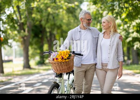 Romantisches Reifes Paar, Das Mit Dem Fahrrad Im Summer Park Spaziert Stockfoto