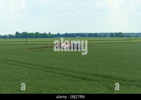 Bei Traktoren mit Düngemitteln werden Pestizide auf dem Feld gesprüht. Stockfoto