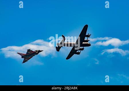 Ein moderner RAF-Taifun-Kampfflugzeug und ein Lancaster-Bomber aus dem Zweiten Weltkrieg fliegen an der Küste des jährlichen Eastbourne Airbourne vorbei Stockfoto