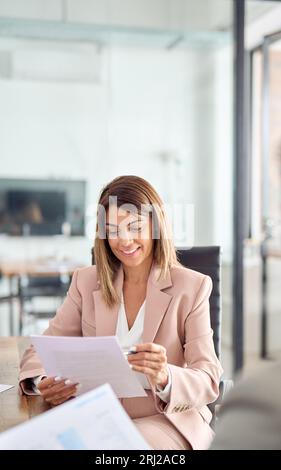 Lächelnde Geschäftsfrau, die Dokumente im Büro diskutiert. Stockfoto