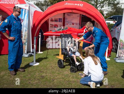 Ein kleines Kind in einem Schubkarren versucht auf einem RAF-Flughelm am Red Arrows Ausstellungsstand in der Militärausstellung neben dem jährlichen Eastbourne Ai Stockfoto