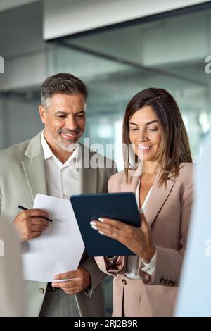 Geschäftige Führungskräfte, die Tablet nutzen, um im Büro zu diskutieren. Stockfoto