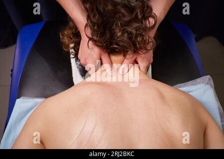 Ganzkörpermassage im Herren-Spa. Der Masseur reibt einem jungen Mann die Schultern und macht eine entspannende Massage. Spa, Massage, Kosmetik für Männer. Top VI Stockfoto