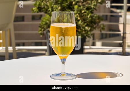 Nahaufnahme eines Glases mit hellem, goldfarbenem Lagerbier auf einem Tisch auf der Außenterrasse einer Hotelbar. Keine Personen. Stockfoto