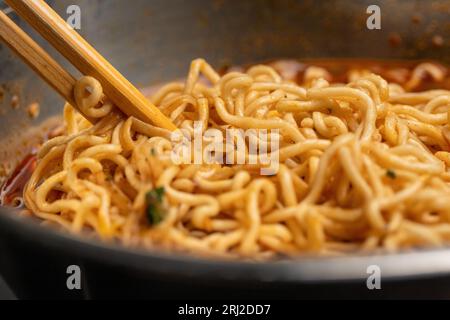 Nahaufnahme von Ramen-Nudeln mit Essstäbchen, die in sie getaucht und gegessen wurden Stockfoto