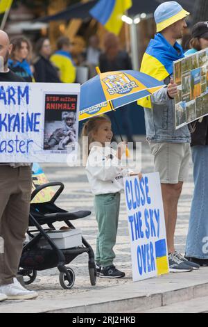 29.10.2022 LISSABON, PORTUGAL: Ukrainischer Protest in Lissabon - kleines Mädchen unter einem blau-gelben Schirm hält ein Poster AM HIMMEL ÜBER DER UKRAINE. Mid-Sho Stockfoto