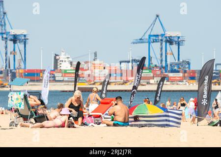 Sonnenbaden mit der Familie am Strand Plaża Stogi Gdańsk oder Stogi mit Blick auf den Hafen von Danzig Nabrzeże Baltic Hub I, Danzig, Polen, Europa, EU Stockfoto