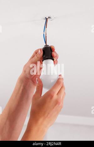 Austausch einer elektrischen Energiesparlampe Nahaufnahme auf einem Deckenhintergrund Stockfoto