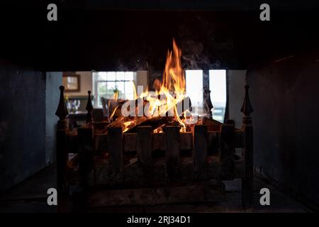 Ein brennender Kamin in traditioneller Umgebung, Rauch bläst aus den offenen Türen Stockfoto