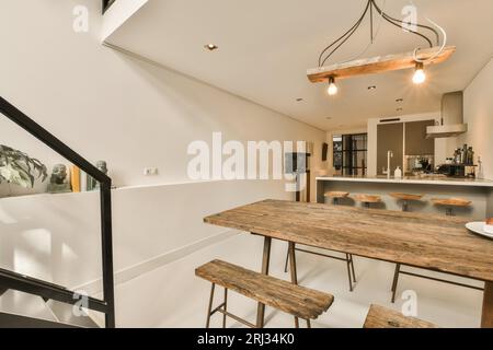 Eine Küche und Essbereich in einem Haus mit weißen Wänden, Hartholzfußboden und einer offenen Treppe, die in die zweite Etage führt Stockfoto