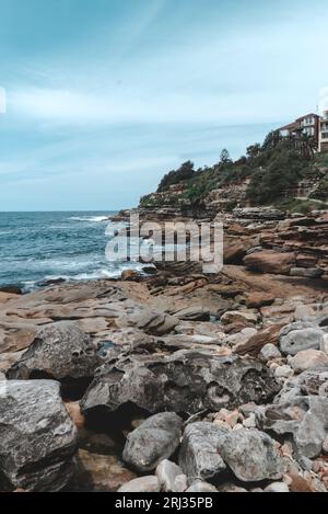 Eine friedliche Küstenlandschaft mit einem felsigen Strand und einem Haus auf einem Hügel Stockfoto