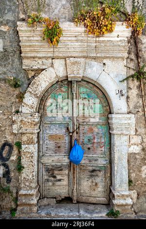 Alte verwitterte Holztür mit erstaunlichem Steinbogen-Sturz in einem verlassenen alten Herrenhaus in der Altstadt von Rethymno, auf Kreta, Griechenland, Europa. Stockfoto