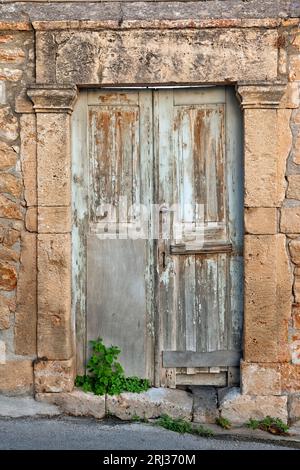 Traditionelle alte Holztür mit einem aus Stein gebauten Sturz, in der Altstadt der Insel Ägina, im Saronischen Golf in der Nähe von Athen, Griechenland, Europa. Stockfoto