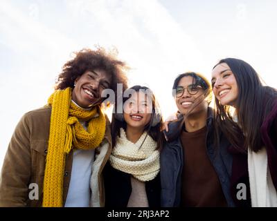 Gruppe von jungen, vielseitigen Teenager-Freunden im Winter, die eine gute Zeit auf der Straße haben Stockfoto