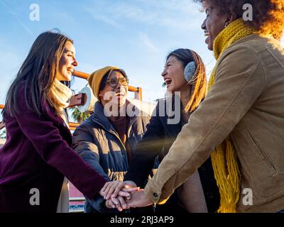 Eine Gruppe verschiedener Freunde hat ihre Hände zusammengelegt und weihnachtsfeiertage im Winter in einer Stadt gefeiert Stockfoto