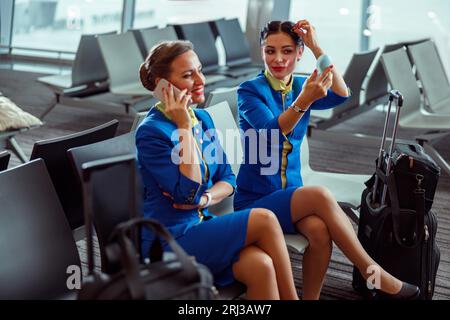 Fröhliche Frauen Stewardessen warten auf den Flug am Flughafen Stockfoto