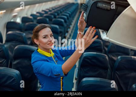 Stewardess: Reisetasche im Gepäckregal über dem Kopf im Flugzeug Stockfoto