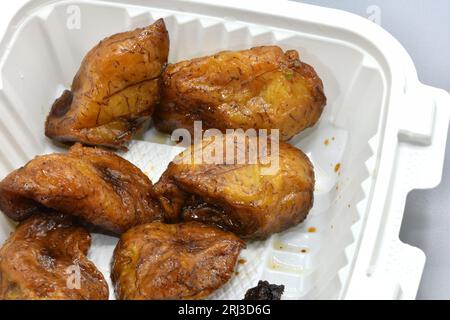 Eine frische Portion gebratener Kochbananen in einem weißen Plastikbehälter. Stockfoto