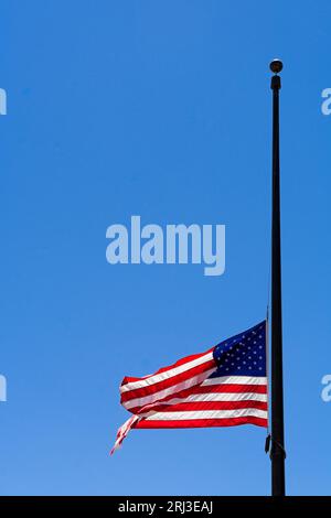 Amerikanische Flagge, die auf halbem Mast gegen den blauen Himmel fliegt Stockfoto