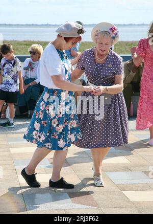Zwei Damen, die ihren Tanz am Meer genießen, beim 1940er-Jahre-Kriegsfest, Lytham St Annes, Lancashire, England, am Sonntag, August 2023 Stockfoto