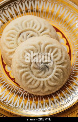 Nahaufnahme von Maamoul (mA'amoul), mit Datteln gefüllte Butterkekse auf kunstvoll gemusterten goldfarbenen und weißen Tellern Stockfoto