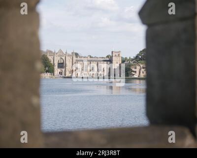 Ein Blick auf Newstead Abbey, ein historisches Anwesen in Nottinghamshire, England, durch ein Steinbogenfenster über dem See Stockfoto