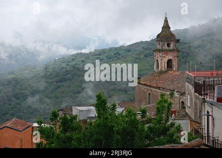 Die Gemeinde Castiglioni di Sicilia in Sizilien, Italien, mit Wohngebäuden, die von üppigen Bäumen und Wolken umgeben sind Stockfoto