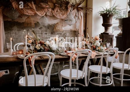 Ein klassisches, elegantes Esszimmer mit einem langen Tisch mit frischen weißen Blumen und flackernden Kerzen Stockfoto