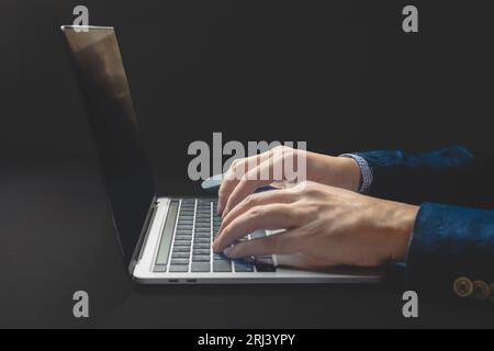 Geschäftsmann, der Hand auf Laptop-Computer auf Bürotisch schreibt, Nahaufnahme Stockfoto
