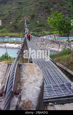 Langer Blick auf die Hängebrücke von Punakha mit Ankerkabel im Vordergrund und Menschen, die auf dem Stahldeck über den Fluss Pho Chhu, Bhutan, gehen Stockfoto