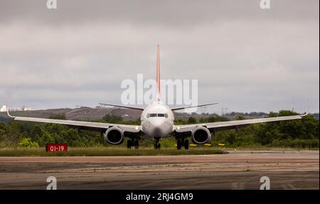 Ein großes Passagierflugzeug auf der Start- und Landebahn neben einem Grasgebiet. Stockfoto