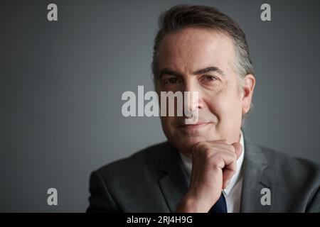 Studio-Porträt eines lächelnden Reifen Unternehmers in grauem Anzug Stockfoto