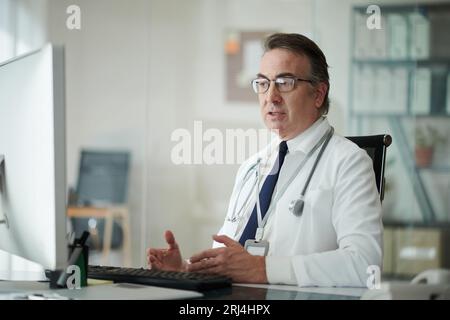 Emotionaler Allgemeinmediziner im Gespräch mit Kollegen im Online-Meeting Stockfoto