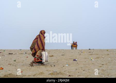 Indian Women walking on Dirty beach side Stock Photo