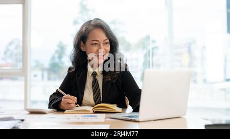 Eine professionelle und erfolgreiche asiatische Geschäftsfrau oder weibliche Führungskraft, die an ihrem Schreibtisch im Büro auf einem Laptop an ihren geschäftlichen Aufgaben arbeitet Stockfoto