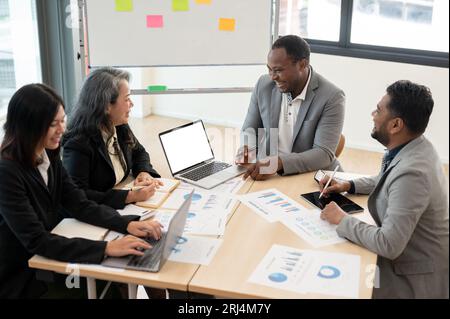 Eine Gruppe von Geschäftsleuten aus verschiedenen ethnischen Gruppen ist in der Sitzung, um gemeinsam im Besprechungsraum ein Brainstorming durchzuführen und sich über einen neuen Investitionsplan für Unternehmen zu beraten. Div Stockfoto