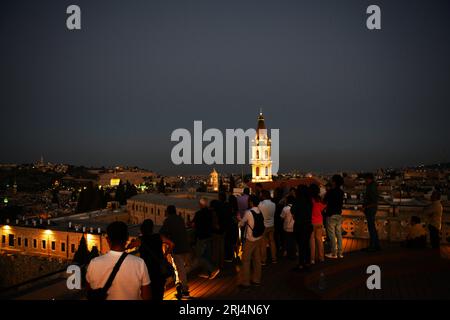 Touristen genießen den Blick auf die Altstadt mit dem beleuchteten Uhrturm des Klosters des Heiligen Erlösers. Jerusalem, Israel. Stockfoto