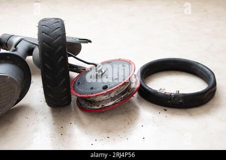 Zerlegter Elektroroller, Reifenpanne und Austausch durch ein neues Rad, Reparatur und Wartung von Elektrotransporten Stockfoto