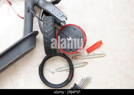 Zerlegter Elektroroller, Reifenpanne und Austausch durch ein neues Rad, Reparatur und Wartung von Elektrotransporten Stockfoto
