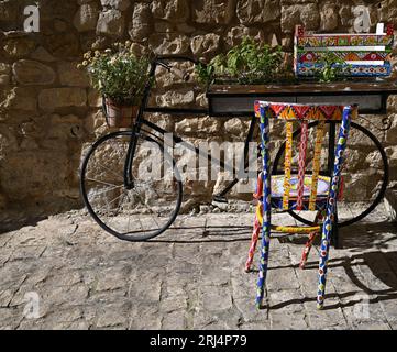 Rustikale Obstkiste aus Holz, handbemalt mit sizilianischen Motiven an einer Steinmauer in Scicli Sicily, Italien. Stockfoto