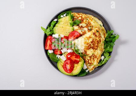 Omelette serviert mit Avocado und Kirschtomaten, gesundes Frühstück auf hellem Hintergrund Stockfoto