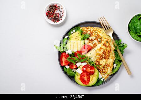 Omelette serviert mit Avocado und Kirschtomaten, gesundes Frühstück auf hellem Hintergrund Stockfoto