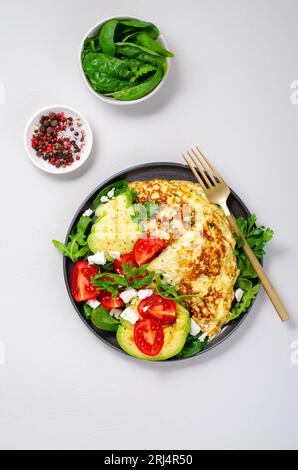 Omelette serviert mit Avocado und Kirschtomaten, gesundes Frühstück auf hellem Hintergrund Stockfoto