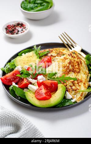 Omelette serviert mit Avocado und Kirschtomaten, gesundes Frühstück auf hellem Hintergrund Stockfoto