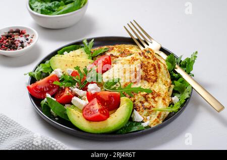 Omelette serviert mit Avocado und Kirschtomaten, gesundes Frühstück auf hellem Hintergrund Stockfoto