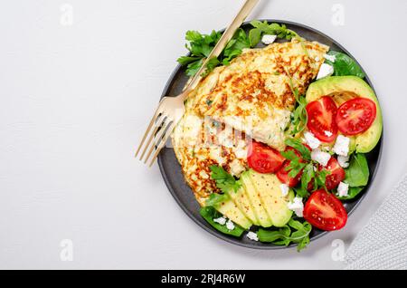 Omelette serviert mit Avocado und Kirschtomaten, gesundes Frühstück auf hellem Hintergrund Stockfoto